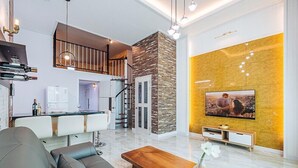A modern living room with a sofa, coffee table, and a TV mounted on a yellow wall. - Majore 2 (Pohang)