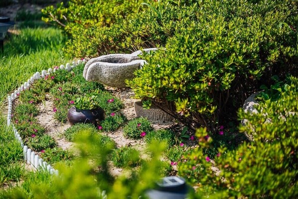 Un jardín con un banco de piedra, una planta en maceta y un camino de piedra.