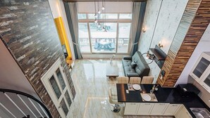 A modern kitchen with a central island, a dining area with a sofa, and a large window offering a view of the outdoors. - Majore 2 (Pohang)