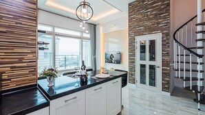 A modern kitchen with a black countertop, white cabinets, and a wooden accent wall. - Majore 2 (Pohang)