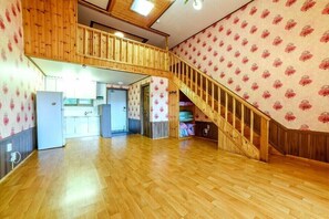 Un vaste espace de vie de style loft, doté d’un escalier en bois, d’un coin cuisine et d’un grand espace ouvert.