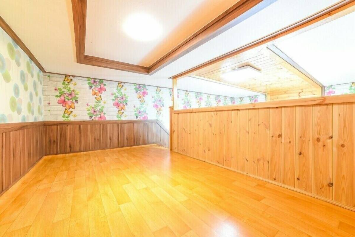 A spacious attic room with wooden flooring, a sloped ceiling, and a skylight.