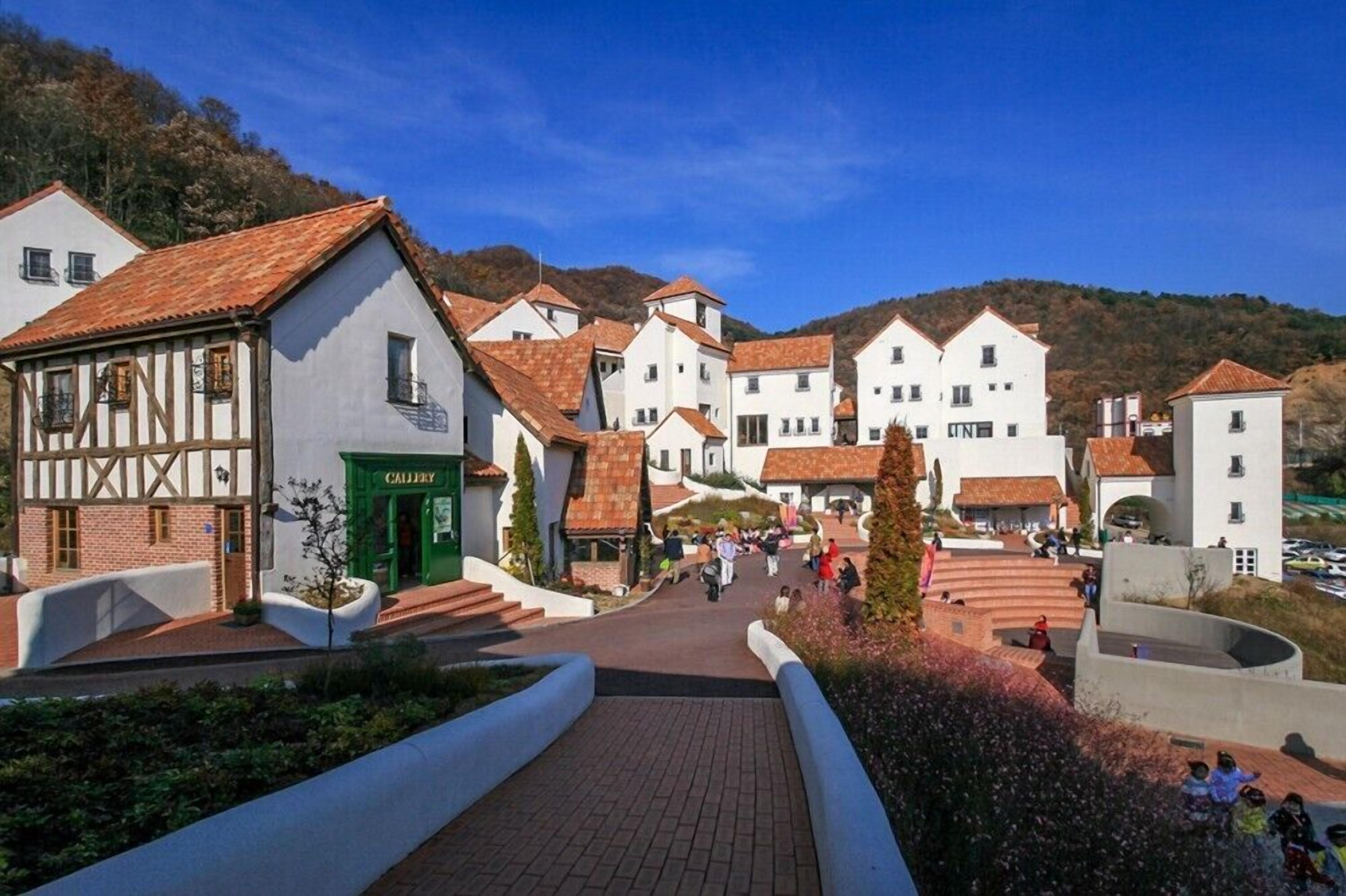 A town square with traditional buildings, a green entrance labeled 'GALLEY,' and a clear sky.