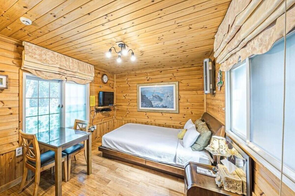 A wooden cabin room with a bed, a table, and chairs.