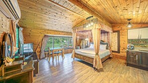 En stuga byggd av trä med en säng med himmelssäng, ett matområde och ett kök.