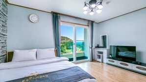 A bedroom with a bed, a television, a clock, and a balcony with a view. - Beach castle hotel & resort (Tongyeong)