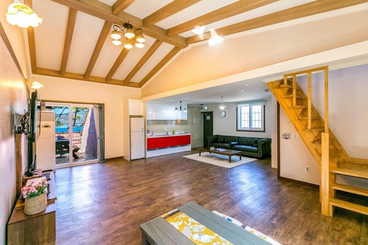 Amplia sala de estar con una escalera de madera, un sofá y una mesa de centro.