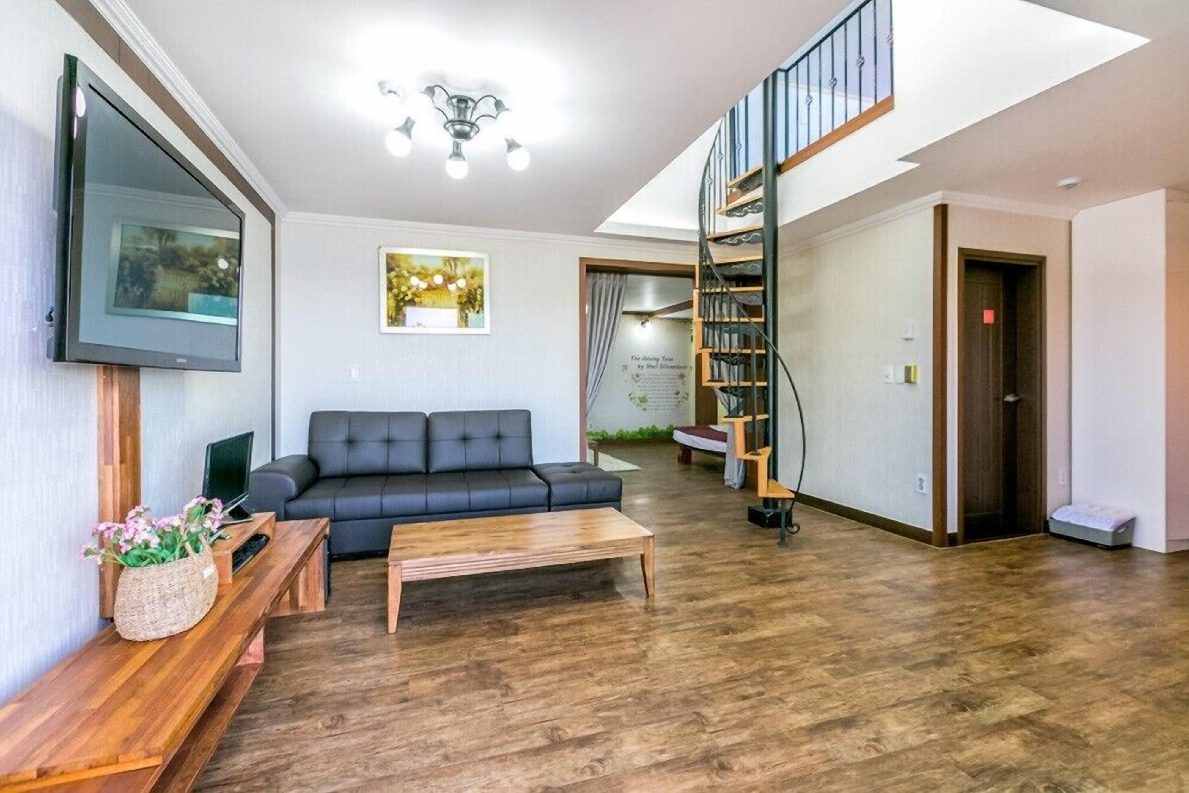Una sala de estar con sofá, mesa de centro, televisor y estanterías.