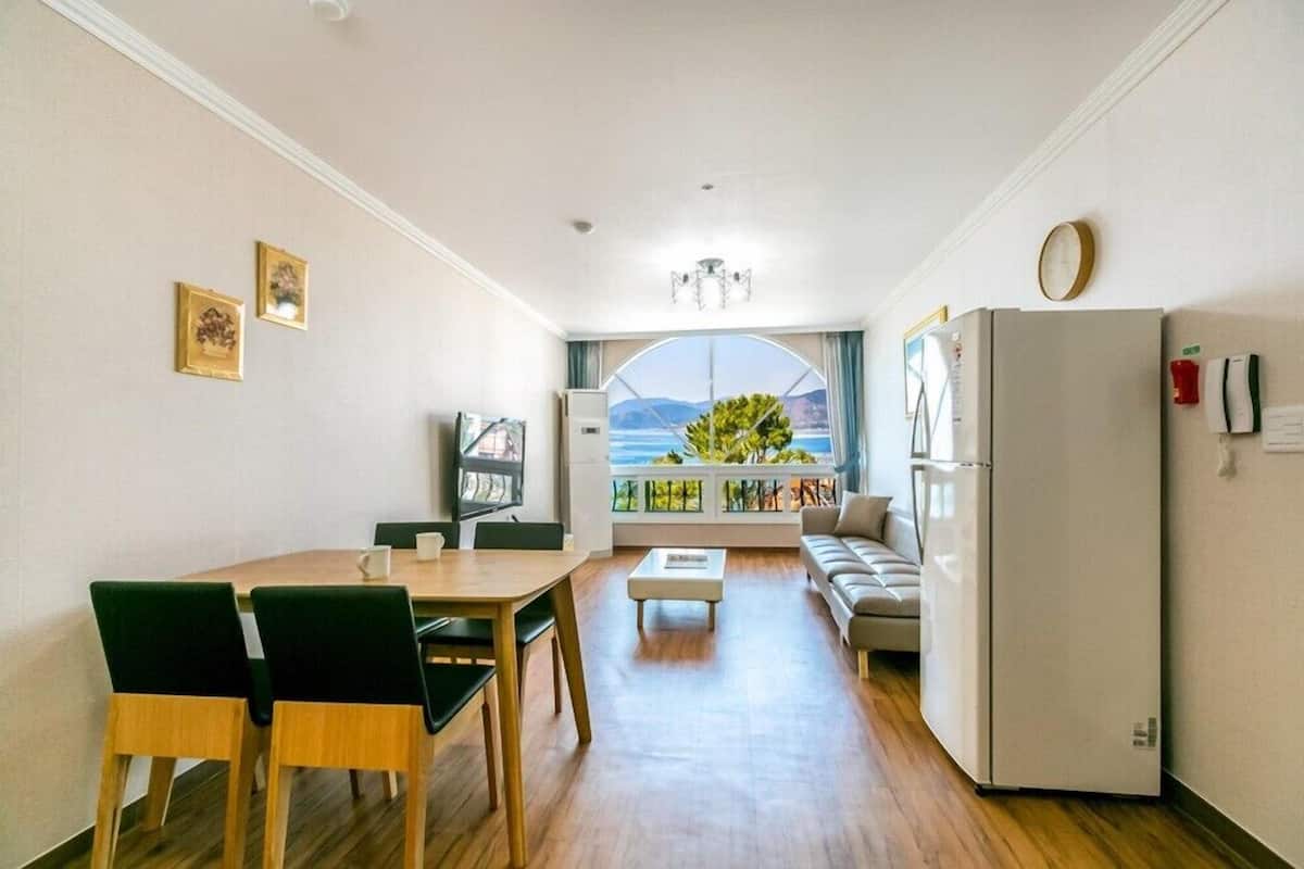 Una sala de estar con comedor, un sofá, una mesa de centro y vistas al exterior.