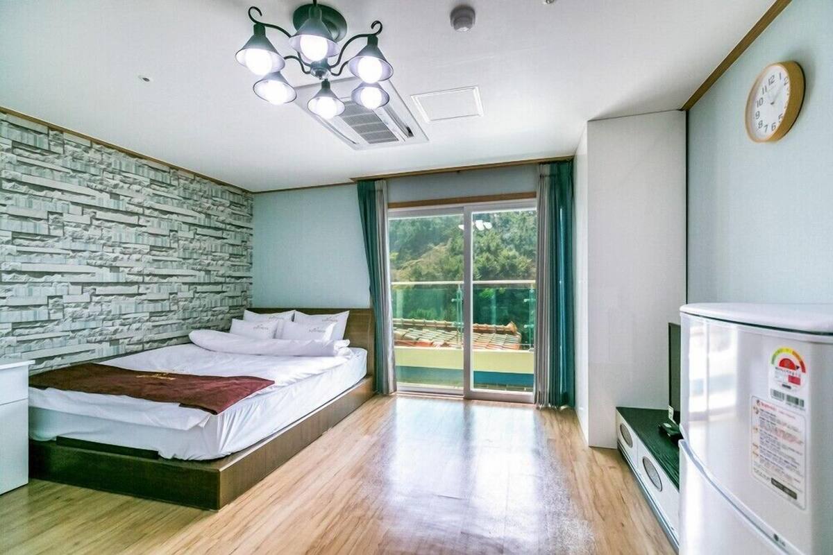 Habitación de hotel con cama, armario empotrado, refrigerador, ventana con vistas y lámpara en el techo.