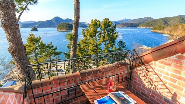 A balcony with a table, a magazine, and a bottle. - Beach castle hotel & resort (Tongyeong)