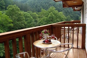 A wooden deck with a round table and chairs, a vase with flowers, and a fruit bowl. - Yeomiji Pension (Gapyeong)