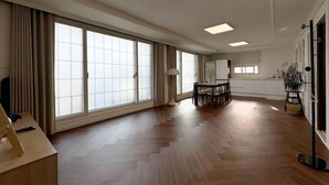 A spacious living area with large windows, a dining table, and a modern ceiling design. - Taeyoung Pension (Pohang)