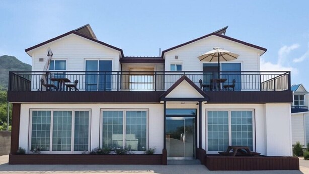 A two-story building with a balcony, large windows, and a covered outdoor seating area. - Taeyoung Pension (Pohang)