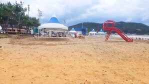 A sandy beach with a white tent and a red slide. - Wolpo Donghae Pension 2 (Pohang)