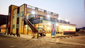 A multi-story building with a staircase leading to the entrance, a balcony on the upper floor, and a sign with Korean characters. - Wolpo Donghae Pension 2 (Pohang)