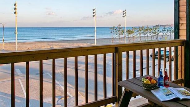 A wooden deck with a view of the beach and ocean. - Wolpo Donghae Pension 2 (Pohang)