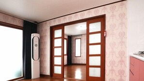 A room with a wooden floor, a large window, and a door leading to another room. - Damoa Pension (Pohang)