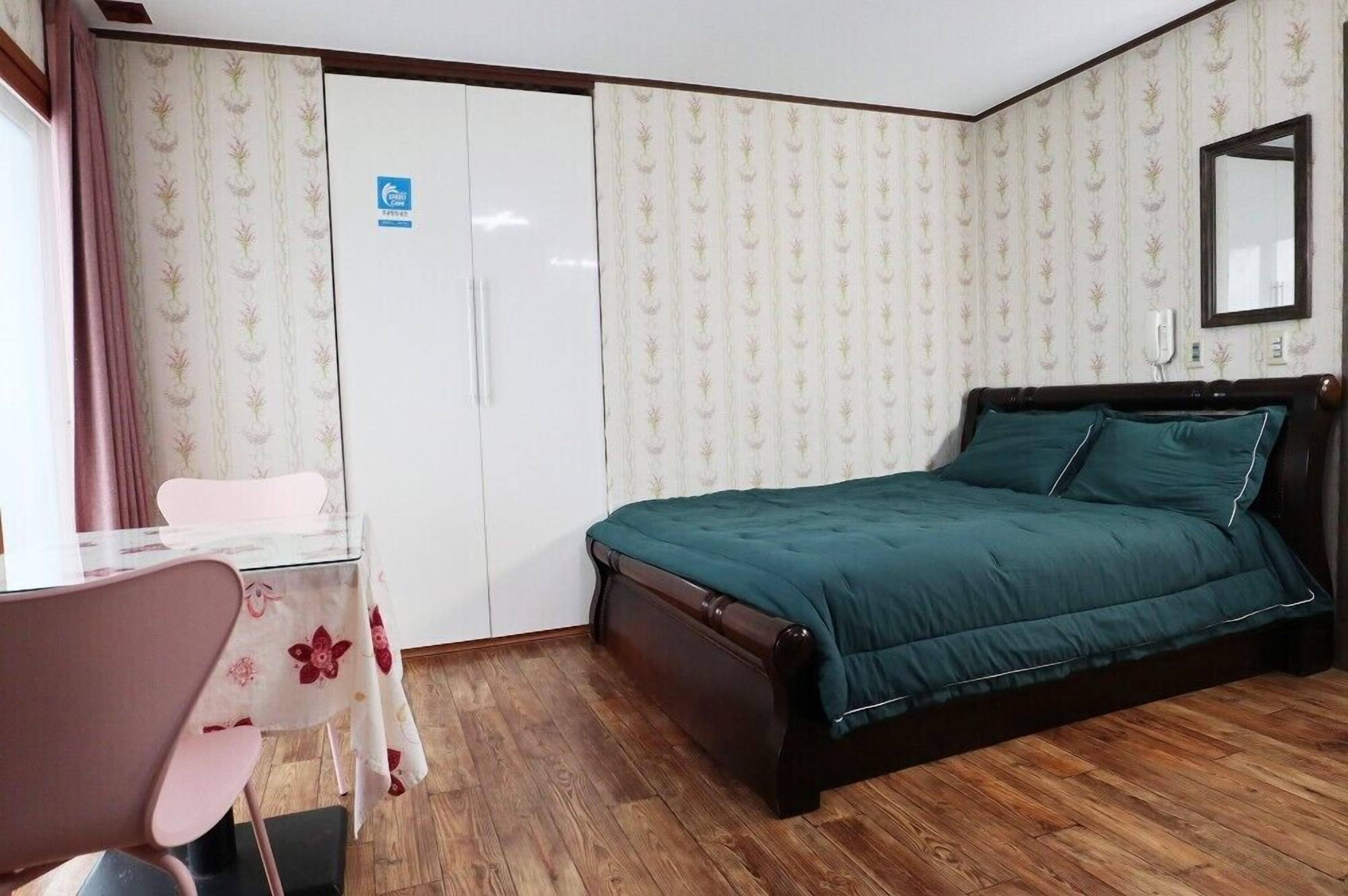 A bedroom with a bed, a desk, and a chair.