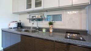Una cucina moderna con un piano di lavoro in granito, lavello in acciaio inossidabile e mobili bianchi.