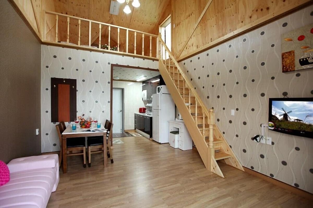 A cozy interior with a dining area, kitchen, and a wooden staircase.