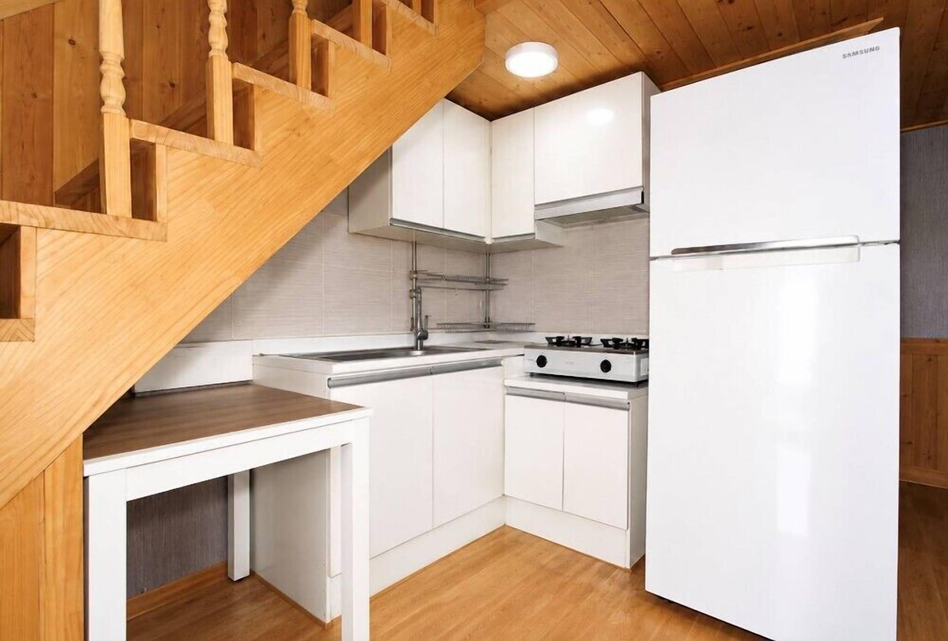 Une cuisine compacte avec des meubles blancs, une cuisinière encastrée et un réfrigérateur Samsung.