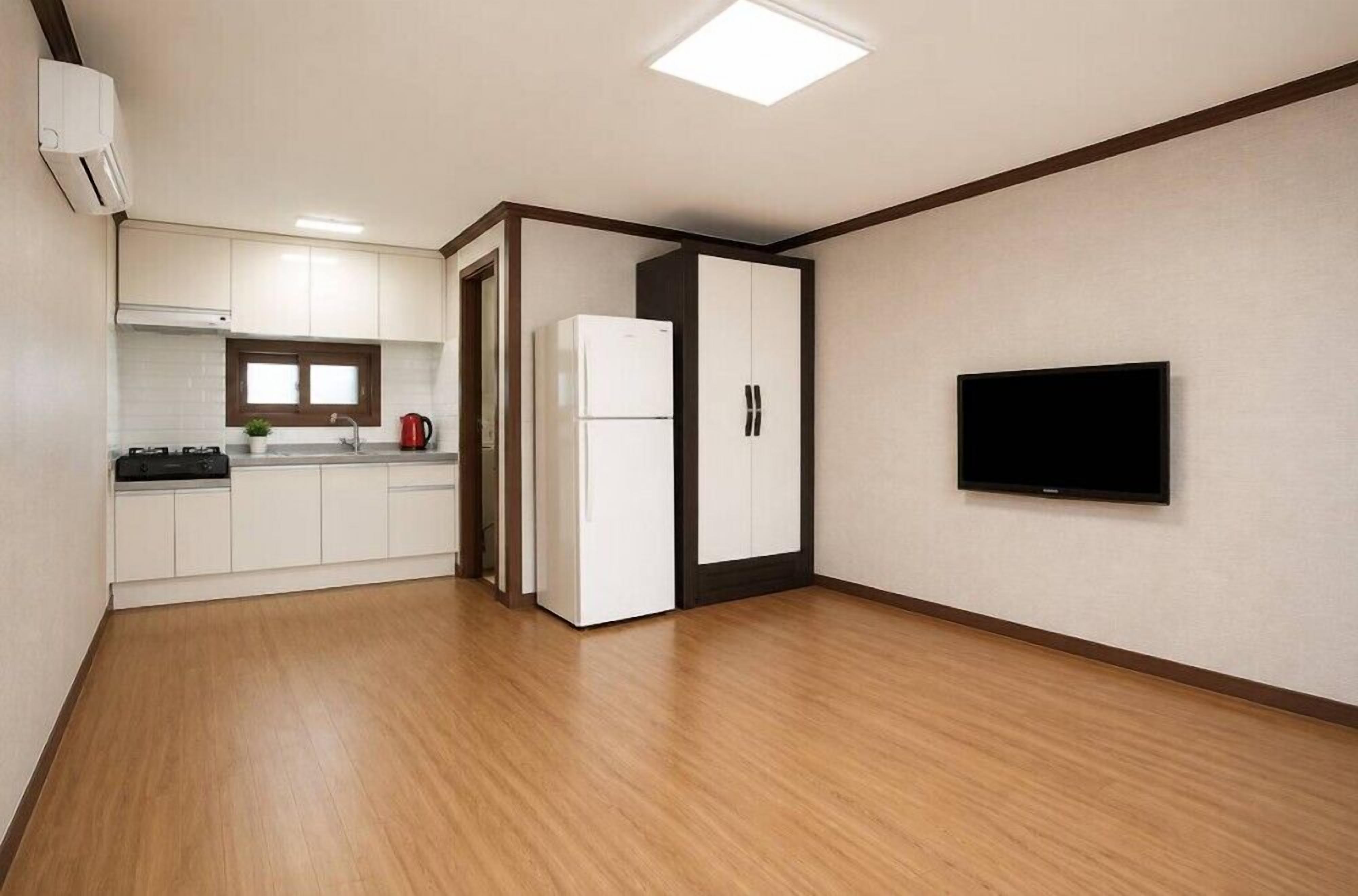 Eine moderne Küche mit weißen Schränken, einem Kühlschrank und einem an der Wand befestigten Flachbildfernseher.