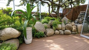 Una terraza de madera con un muro de piedra y plantas.