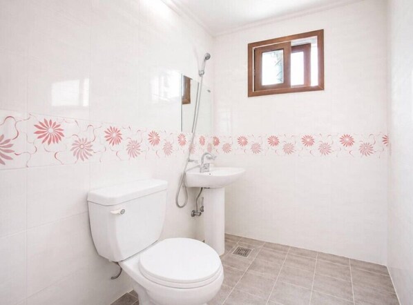 A bathroom with a toilet, sink, and shower.