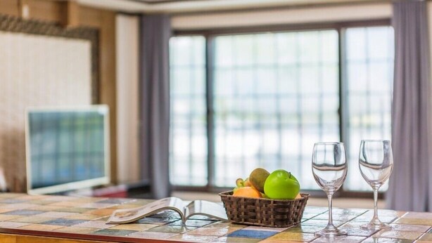 A room with a tiled table, a basket of fruit, and two empty wine glasses. - Serence Pension (Gapyeong)