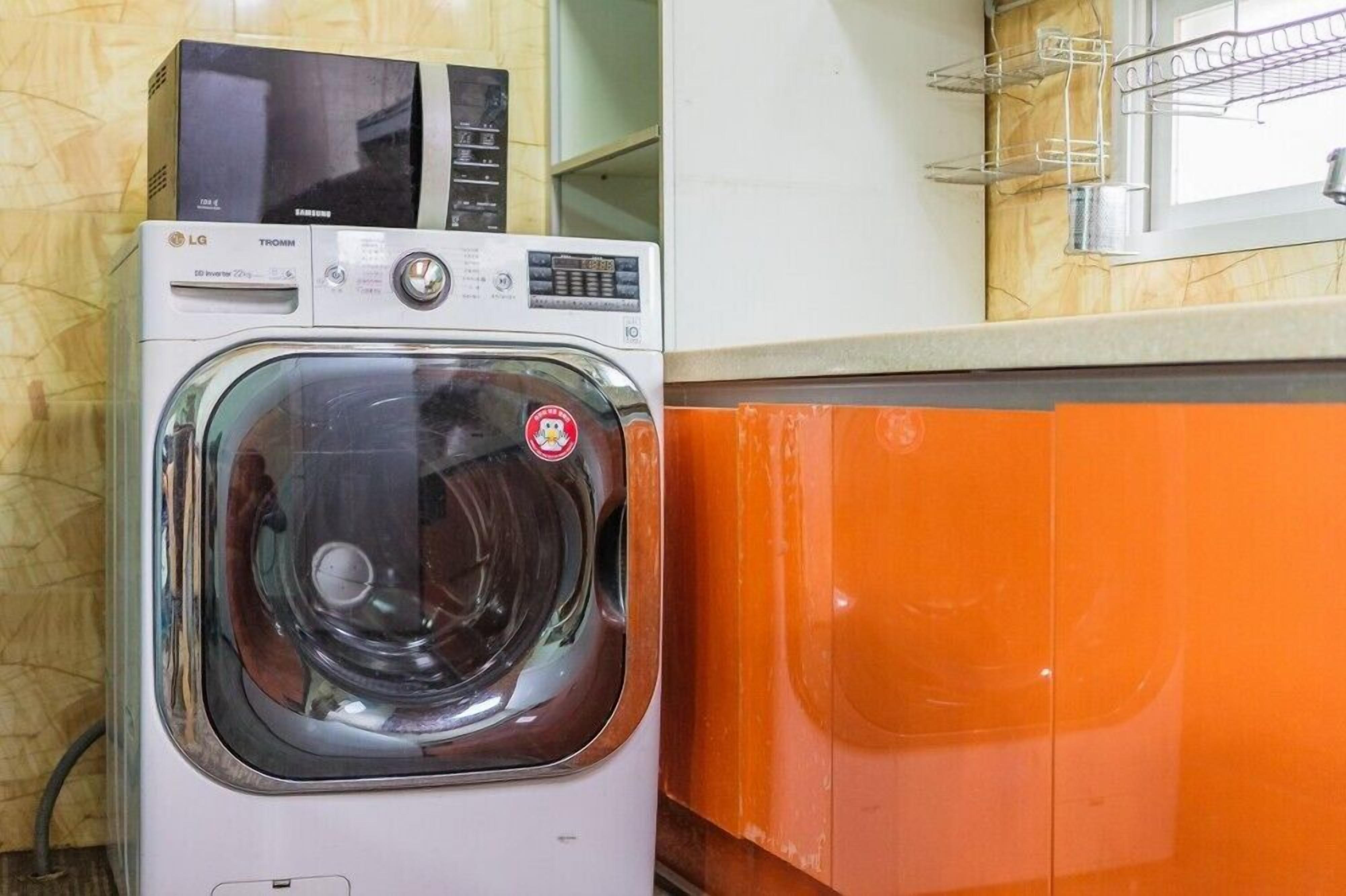 Un lave-linge à chargement frontal doté d’un panneau de commande et d’un four à micro-ondes placé sur le dessus.