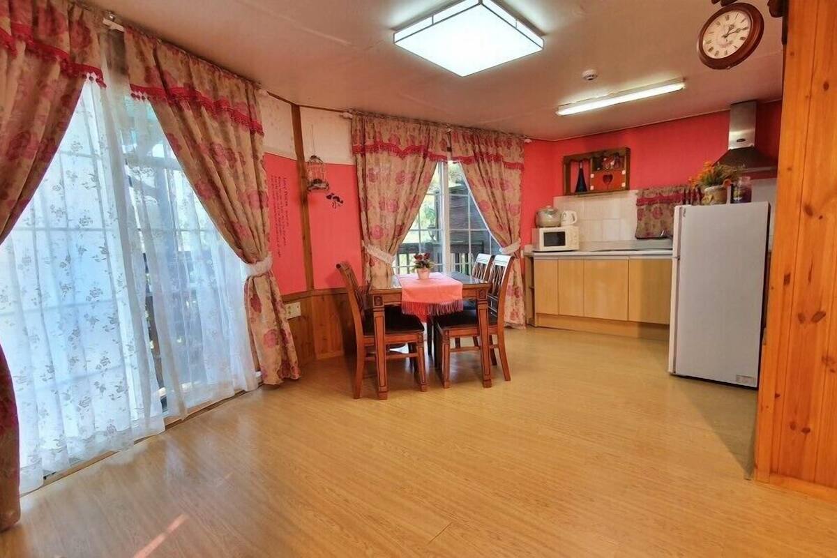 Eine gemütliche Küche mit Holzausstattung, einem Esstisch mit Stühlen und einem Kühlschrank.