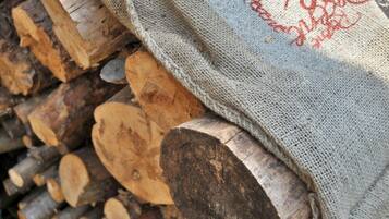 Una bossa de jute amb text vermell que cobreix parcialment un munt de llogs tallats.
