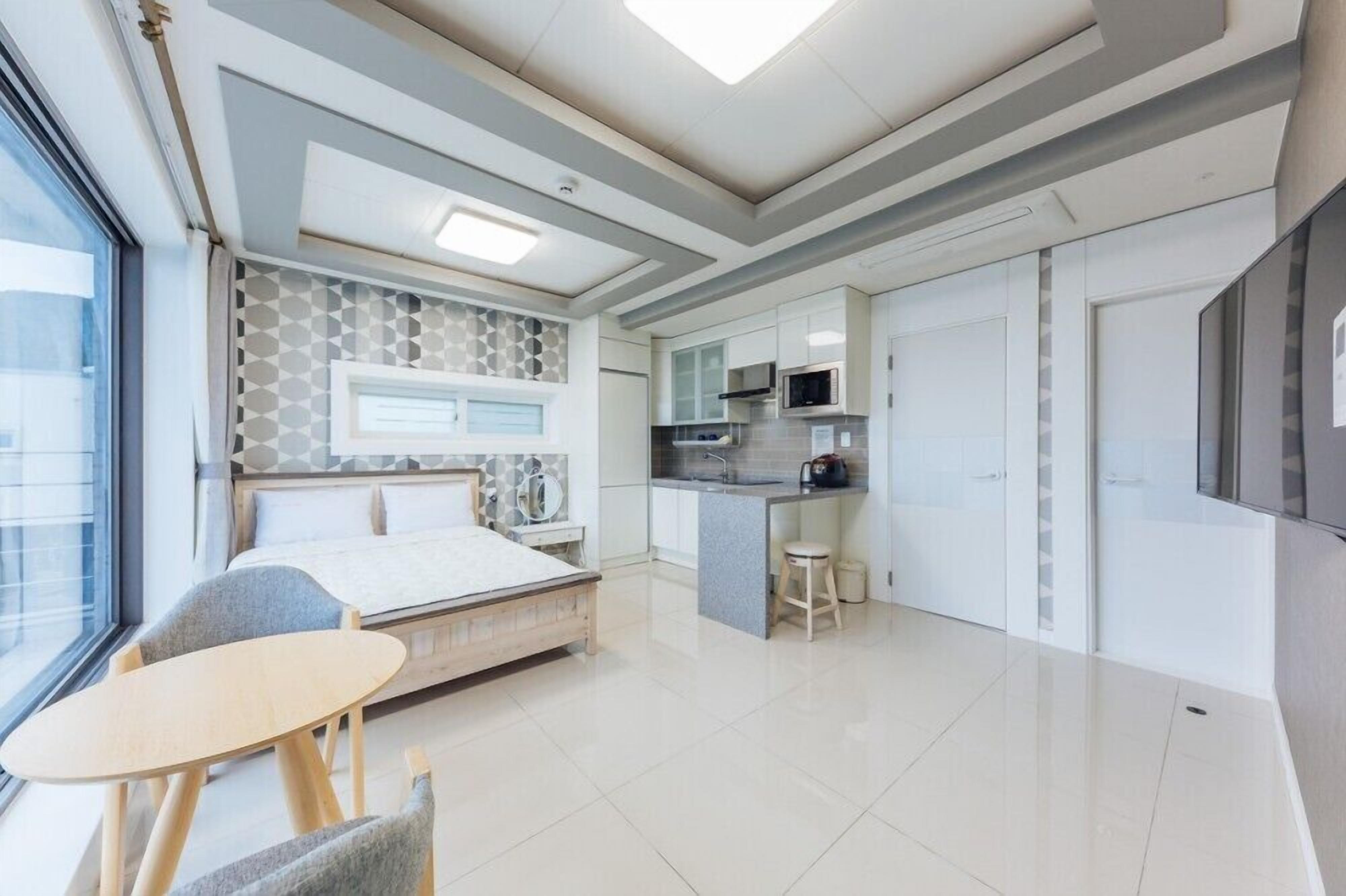 Un dormitorio moderno con cama, mesita de noche y una pequeña zona de estar con mesa y sillas.
