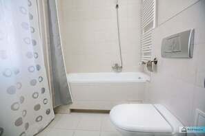 A bathroom with a bathtub, toilet, and shower.