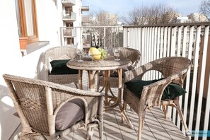 Eine Sitzgruppe im Freien aus Korbmöbeln mit einem runden Tisch, Stühlen und einer Obstschale.