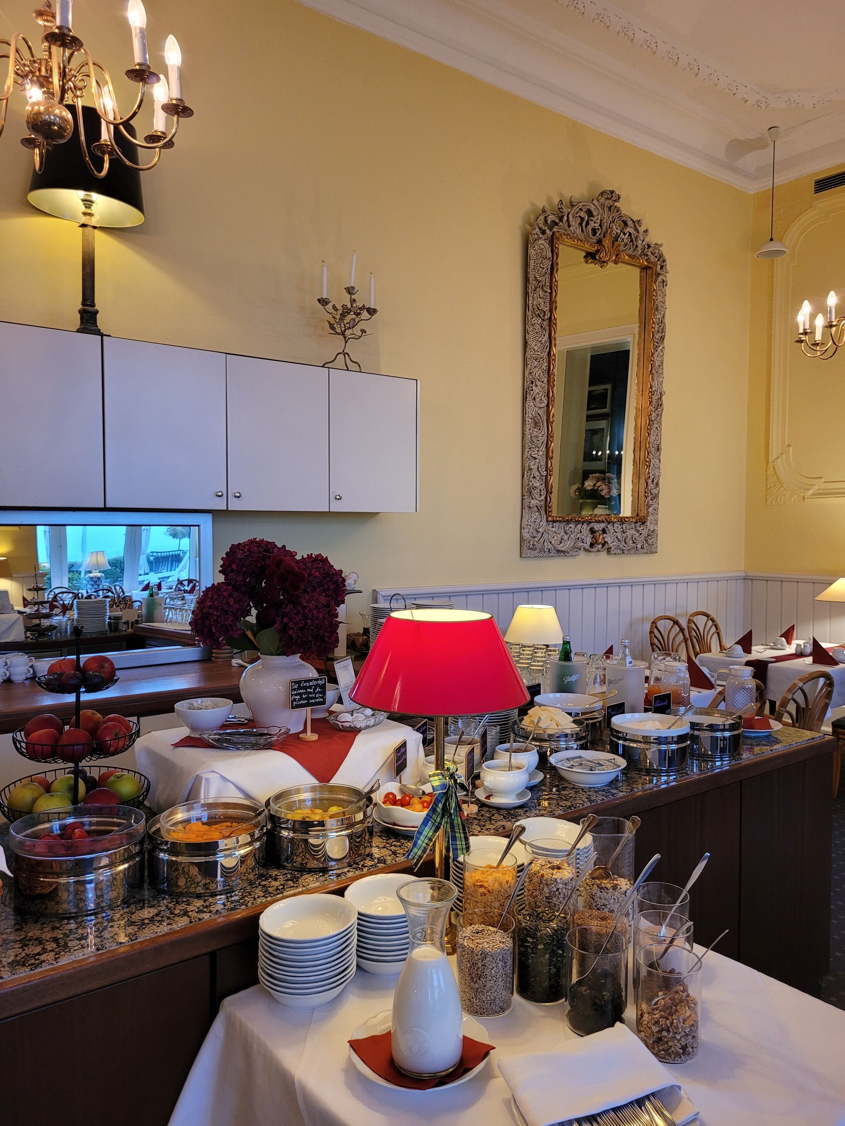 A buffet setup with various food items and a mirror on the wall.