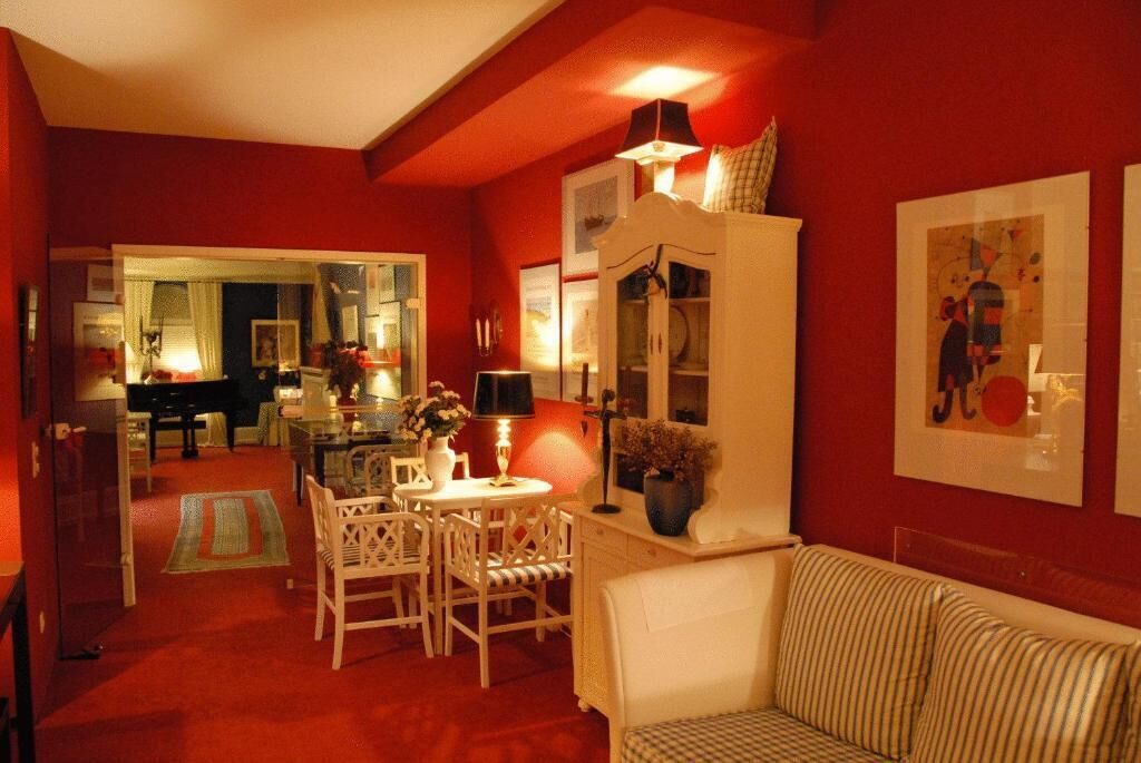 A cozy living room with a striped sofa, a dining area with a table and chairs, and a kitchen in the background.