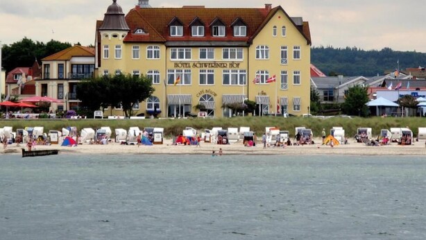 Un hôtel avec une enseigne bien visible, de nombreuses fenêtres et une plage au premier plan.