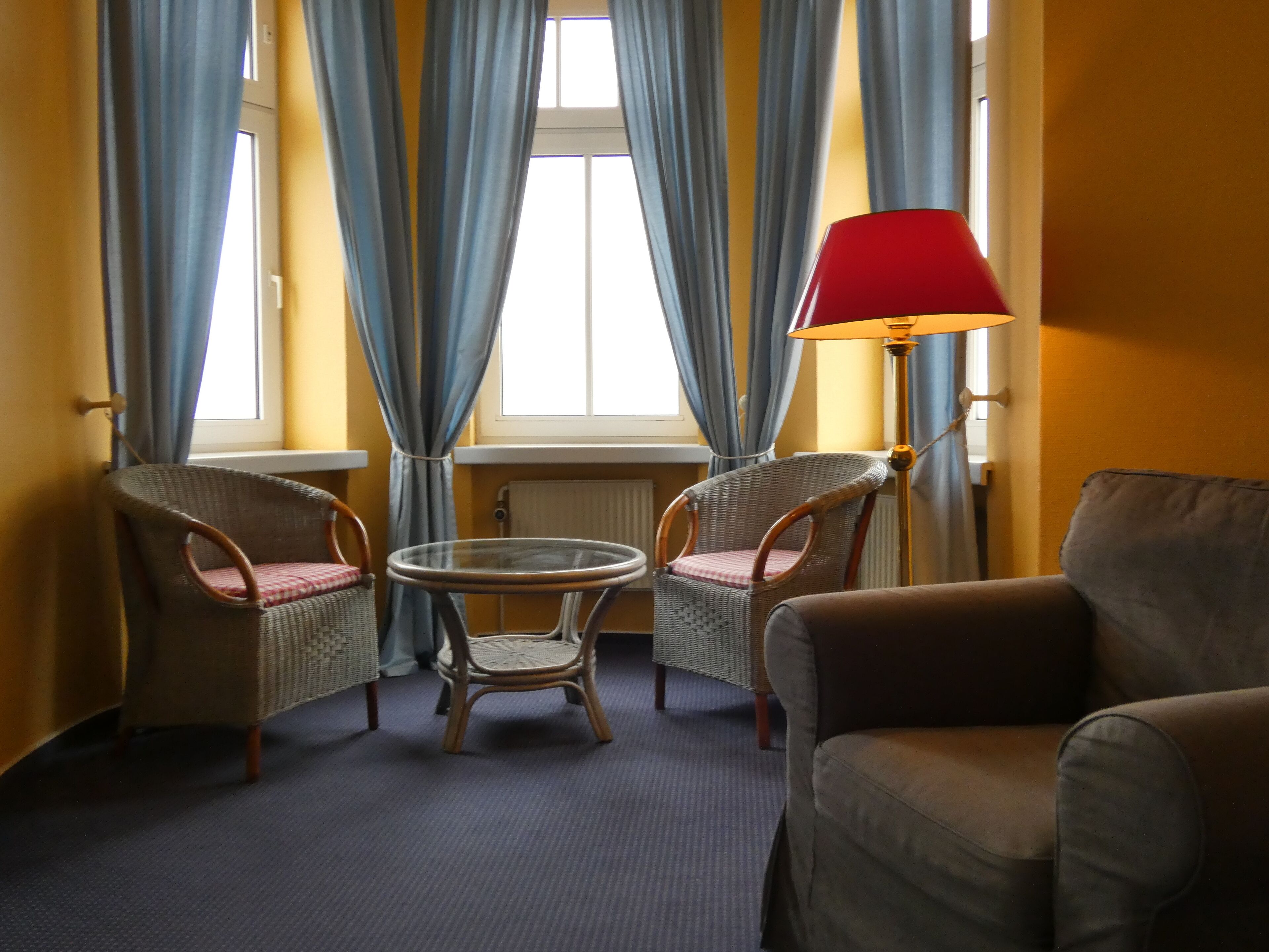 A room with two wicker chairs, a round table, a sofa, and a floor lamp.