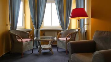 A room with two wicker chairs, a round table, a sofa, and a floor lamp.