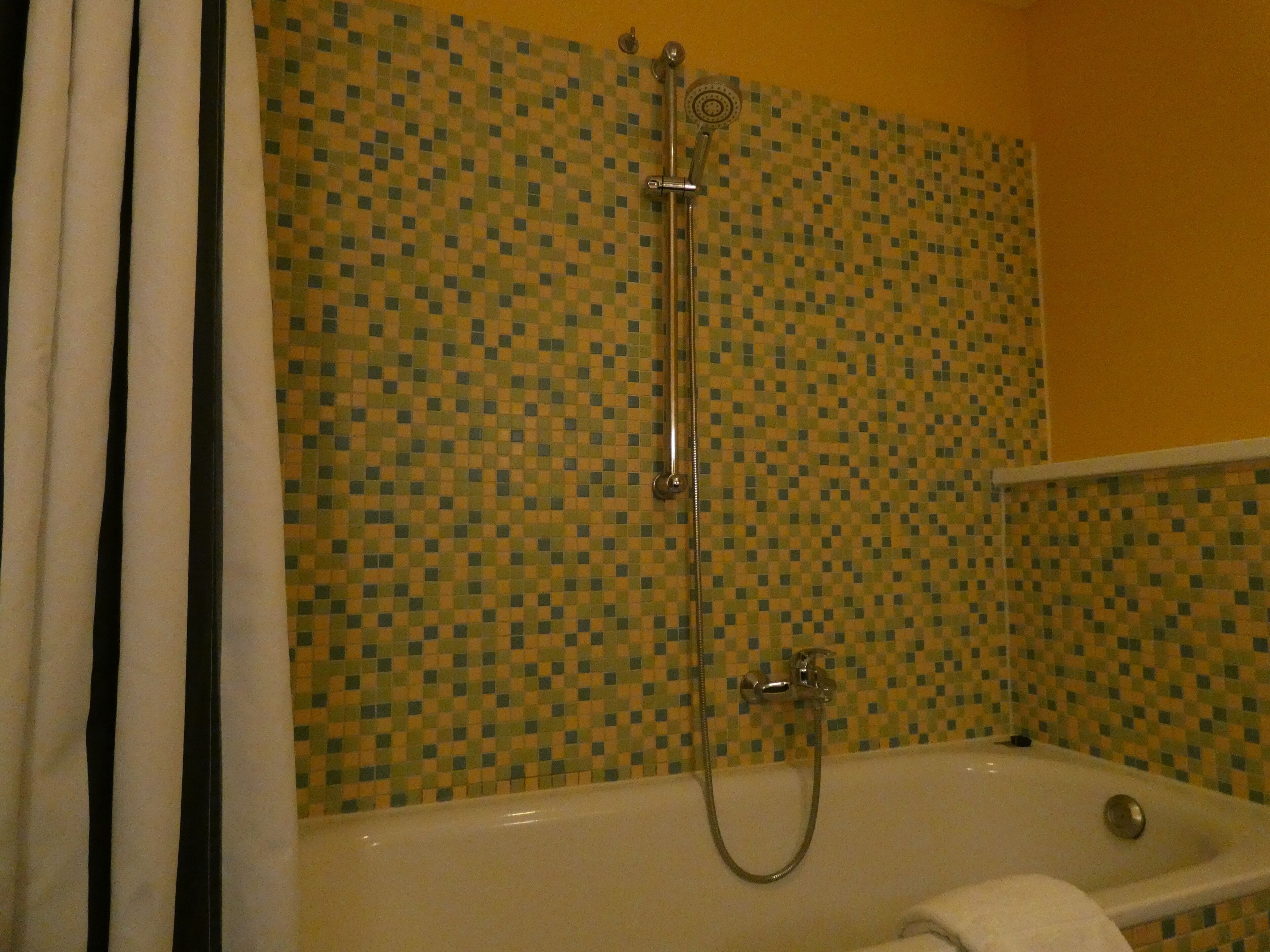 Un baño con ducha, bañera y pared de azulejos.
