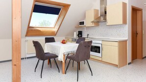 A compact kitchen with a skylight, a dining table with chairs, and a microwave.
