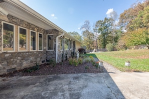 A stone house with a covered porch, a well-maintained lawn, and a stone pathway leading to the entrance.