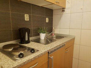 Una cocina con encimera de granito, cafetera, lavamanos y planta en maceta.