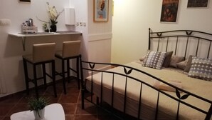 A compact bedroom with a bed, a small table, and a seating area with chairs.