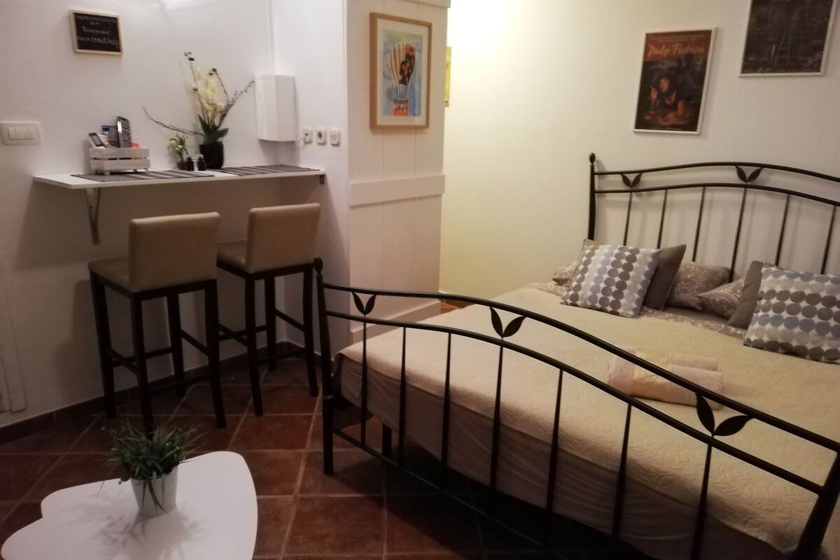 A compact bedroom with a bed, a small table, and a seating area with chairs.