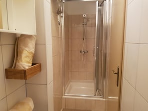 Un baño con ducha, inodoro y un perchero para toallas.