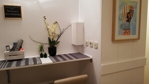 A reception desk with a potted plant, a framed painting, and a sign with WiFi and password information.