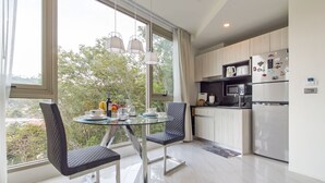 Une cuisine moderne avec un coin repas, de grandes fenêtres et une vue sur la verdure.
